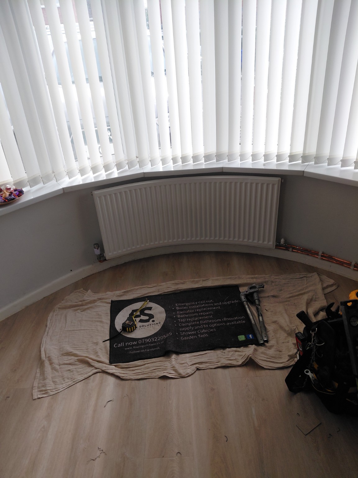 White curved radiator fitted to follow a bay window by Flowing Solutions