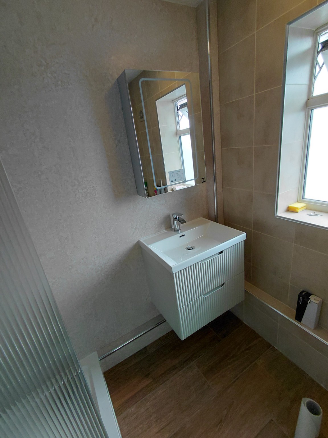 Fluted floating vanity and illuminated mirror fitted by Flowing Solutions